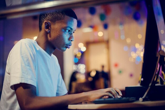 Niño afroamericano usando una computadora por la noche