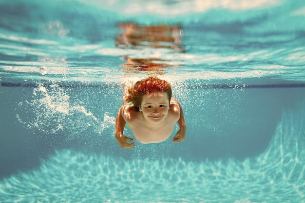 Niño bajo el agua nadando en la piscina Niño lindo niño nadando en la piscina bajo el agua