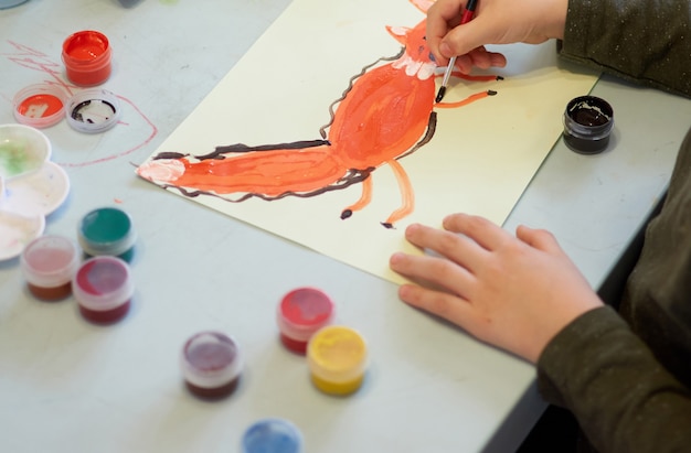 El niño se ahoga una imagen durante la lección de arte en línea en el teléfono celular, cuarentena Covid-19, autoaislamiento, concepto de educación en línea, educación en el hogar. Niños en casa, guardería cerrada, guardería. Niño de 6 años.