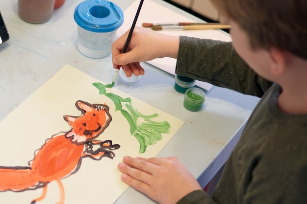 El niño se ahoga una imagen durante la lección de arte en línea en el teléfono celular, cuarentena Covid-19, autoaislamiento, concepto de educación en línea, educación en el hogar. Niños en casa, guardería cerrada, guardería. Niño de 6 años.