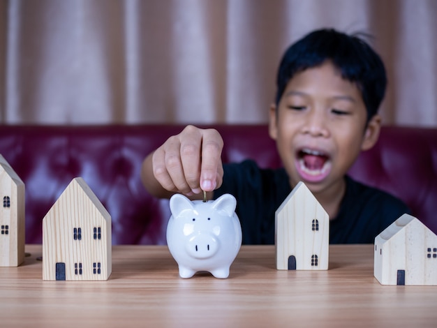 Niño ahorrando dinero en una alcancía de cerdo blanco. Concepto de ahorro. Ahorrando para el futuro.