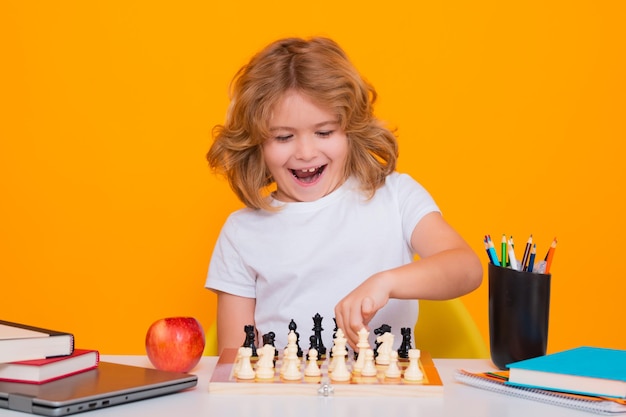 Niño con ajedrez sobre fondo de estudio aislado amarillo niño jugando ajedrez niño inteligente pensando en