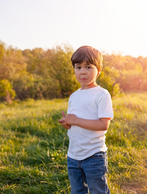 un niño se para al aire libre bajo los rayos del sol poniente