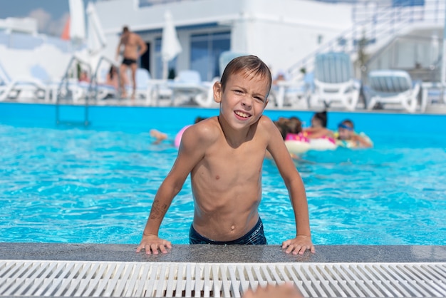 El niño al lado de la piscina está sonriendo La piscina al aire libre