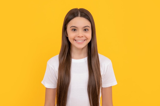 Niño alegre con cabello largo belleza y moda modelo de moda femenina mirada bonita de niña retrato de niño feliz sobre fondo amarillo expresa emociones positivas