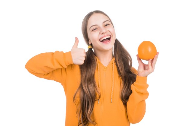 niño alegre con cítricos naranja lleno de vitaminas aisladas en blanco pulgar hacia arriba