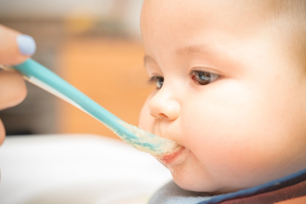 Foto niño alegre come comida con una cuchara retrato de niño feliz en silla alta