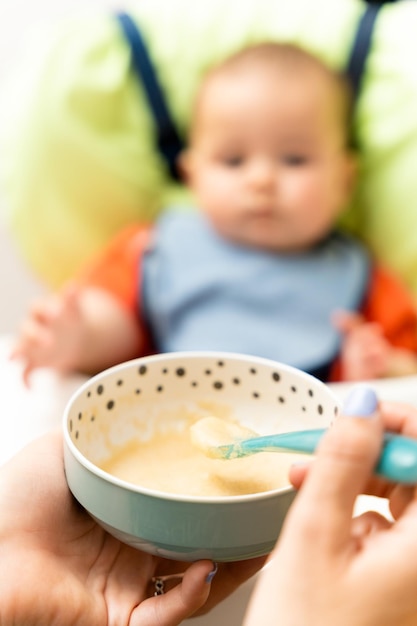 Foto niño alegre come comida con una cuchara retrato de niño feliz en silla alta