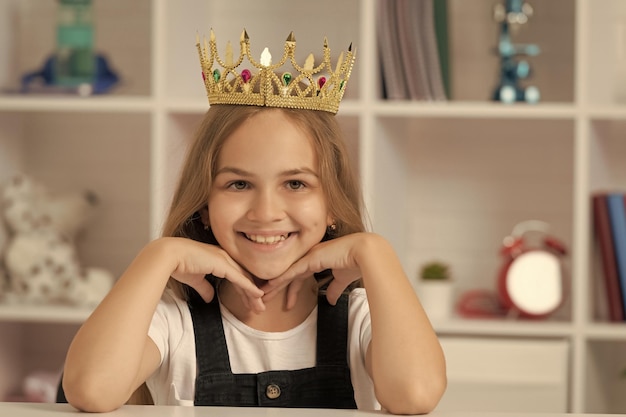 Niño alegre en la corona de la reina en el aula de la escuela