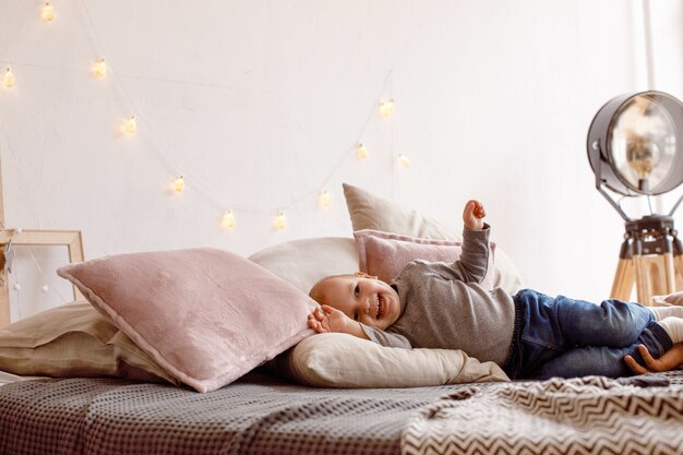 Niño alegre divirtiéndose en la cama