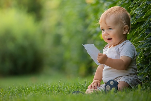 Un niño alegre y feliz está sentado en un césped verde