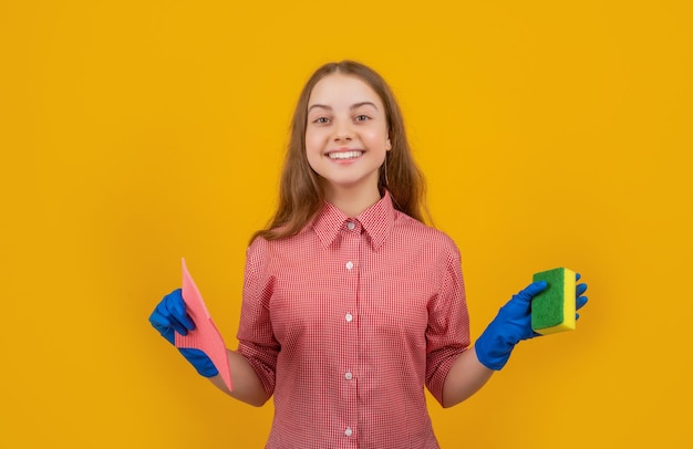 Foto niño alegre feliz en guantes de goma con esponja sobre fondo amarillo