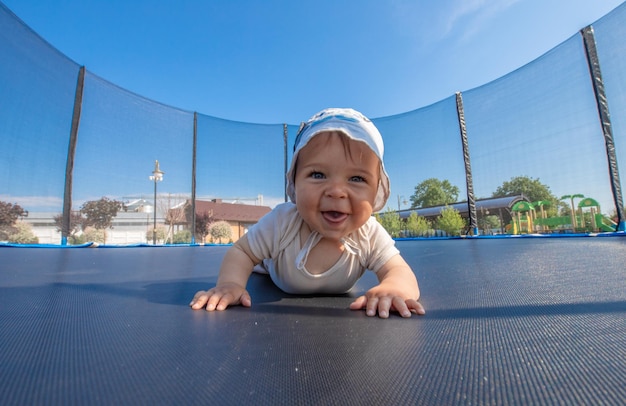 Niño alegre feliz en un trampolín en un cálido día de verano