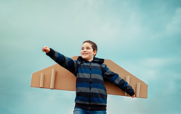 Niño alegre jugando con avión de alas de papel. Concepto de turismo