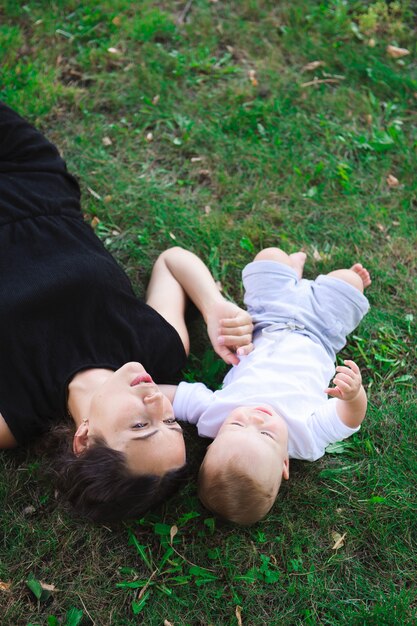 Niño alegre lindo con madre jugar al aire libre en el parque