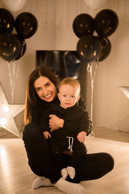 Niño alegre lindo con la madre jugar en el interior.