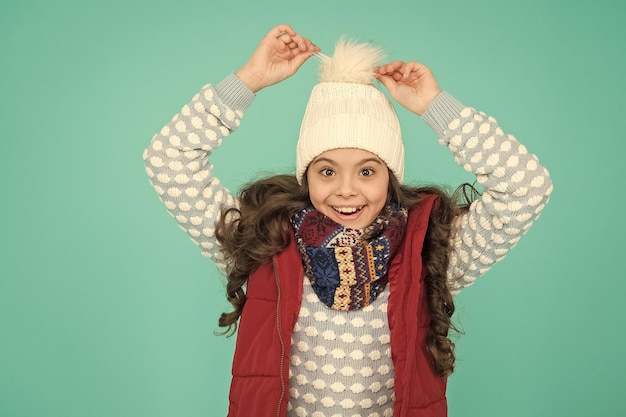 Niño alegre en ropa de invierno cálido de bufanda de punto y suéter en vacaciones de año nuevo infancia feliz