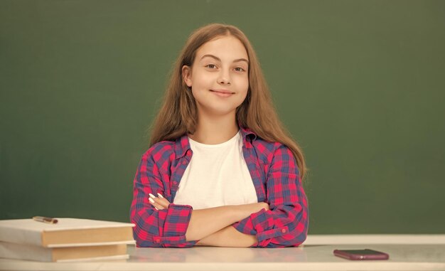 Niño alegre sentado en el aula en la pizarra septiembre