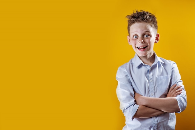 Un niño alegre se para y sonríe con una camisa ligera