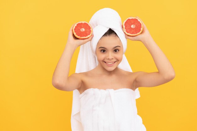 Niño alegre en toalla con pomelo sobre fondo amarillo