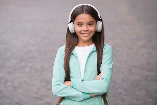 Niño alegre use auriculares con canción de música al aire libre disfrutando de la melodía de regreso a la escuela