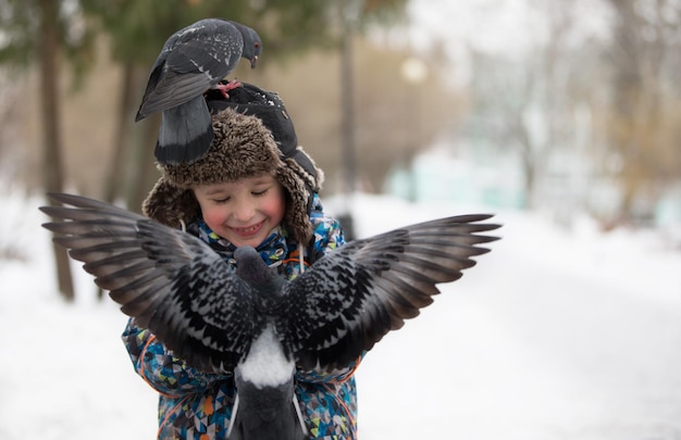 Un niño alimenta palomas de una mano de invierno. Alimentando a las aves.