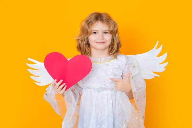 Niño ángel señalando en papel corazón rojo punto gesto día de san valentín niño con alas de ángel studio por