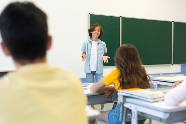 Foto niño de ángulo bajo que se presenta frente a la clase