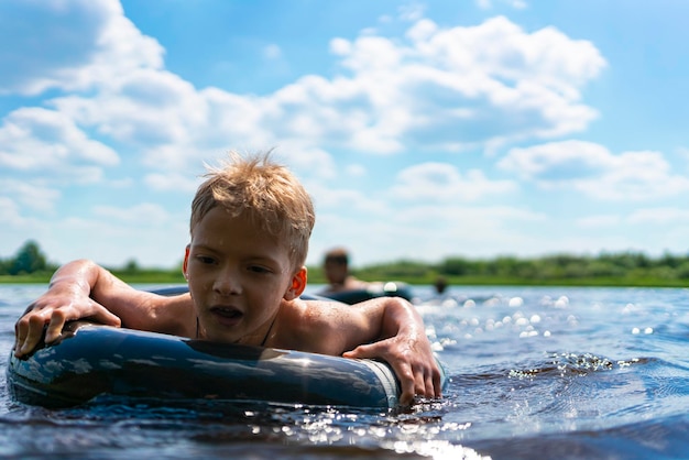 Niño con un anillo de goma flota en el verano niño nada en el lago en verano entretenimiento infantil de verano