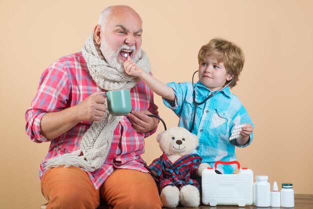 Niño apoyando a abuelo discapacitado Anciano con bufanda sosteniendo un blister de pastillas en sus manos