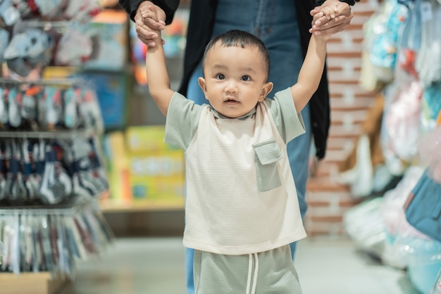 Niño aprende a caminar mientras compra en la tienda para bebés