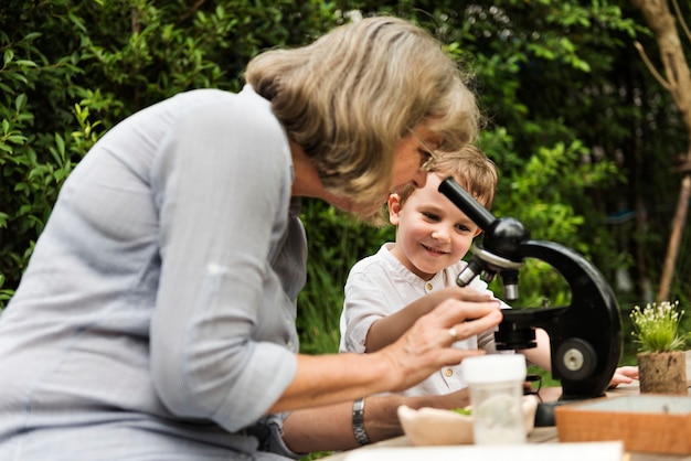 Niño aprendiendo con anciana y telescopio