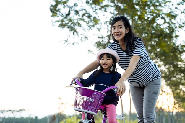 Niño aprendiendo a andar en bicicleta con la madre