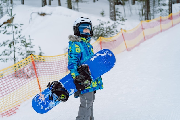 Niño aprendiendo a andar en snowboard de pie en la pista de esquí Ocio de invierno