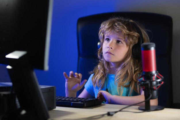 Niño aprendiendo en línea por la noche usando una computadora de escritorio en la sala de estar en casa