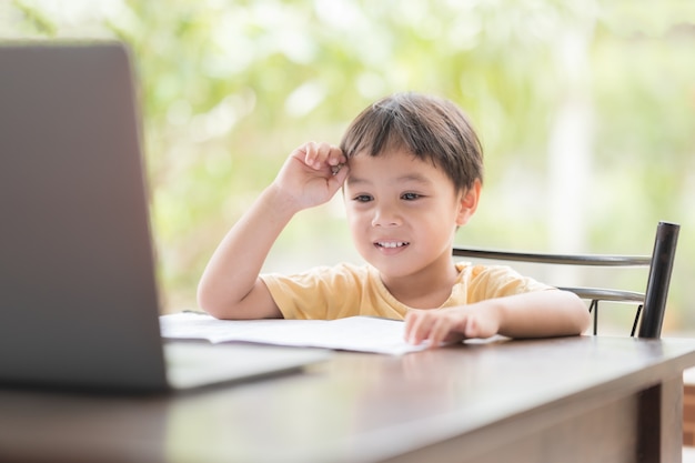 El niño aprendiendo en línea y usando laptop.