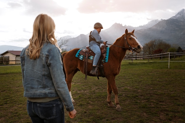 Foto niño aprendiendo a montar a caballo