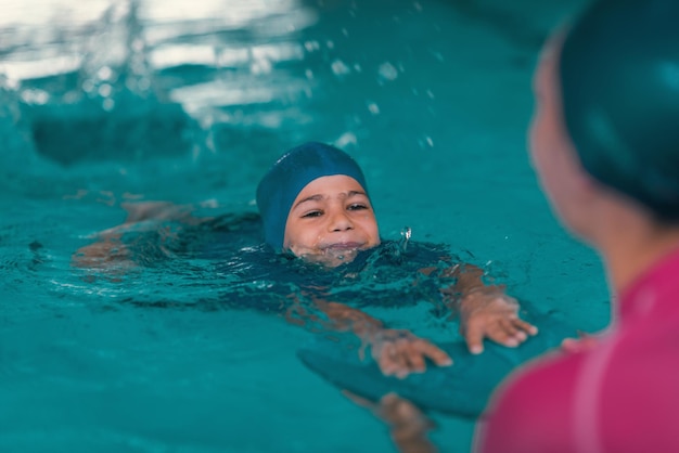 Niño aprendiendo a nadar en la piscina con el maestro