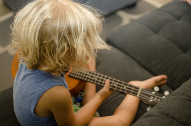 Niño aprendiendo a tocar un ukelele de madera.