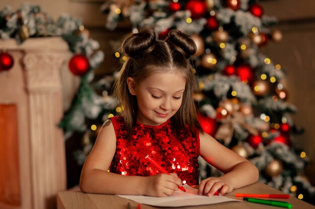 Un niño en el árbol de Navidad escribe una carta a Santa Claus