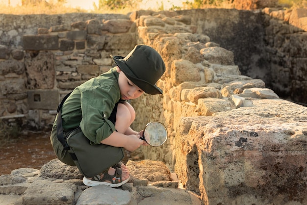 Niño arqueólogo en ropa caqui estudiando las ruinas de una ciudad antigua Concepto diverso de trabajos no tradicionales