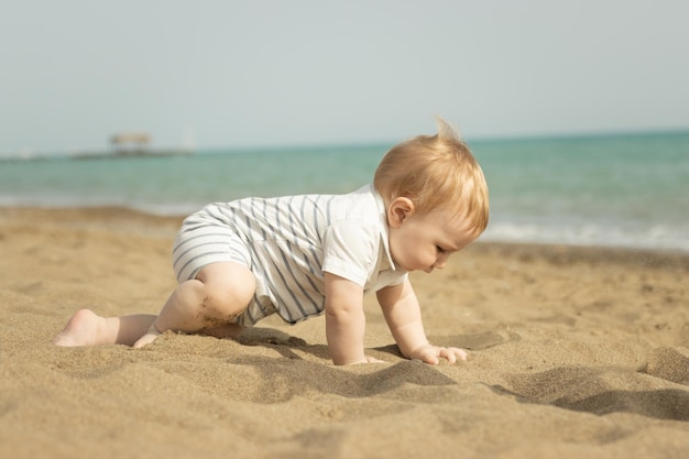 Un niño arrastrándose sobre la arena de la playa Mid shot