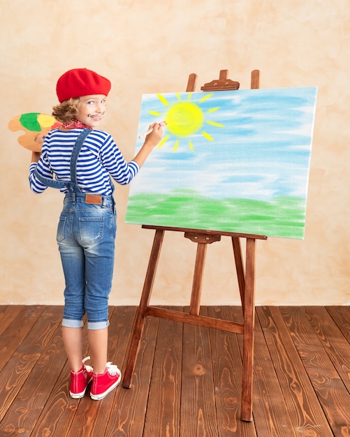 Niño artista pintando el cuadro sobre lienzo.