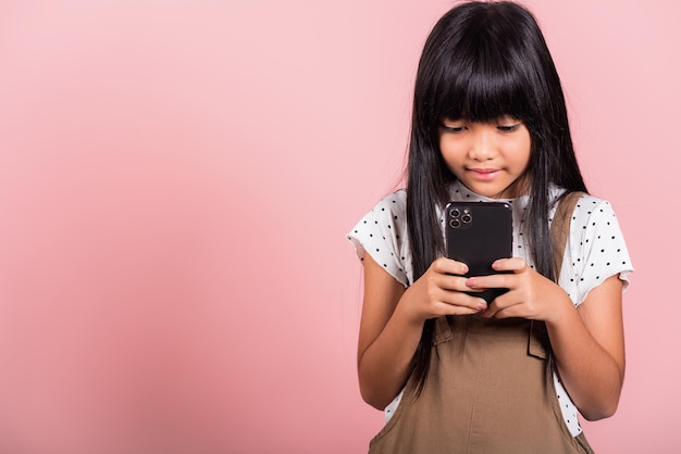 Niño asiático de 10 años disfrutando del uso de teléfonos móviles para redes sociales