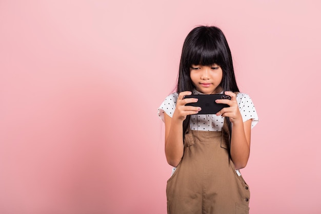 Niño asiático de 10 años disfrutando del uso de teléfonos móviles para redes sociales