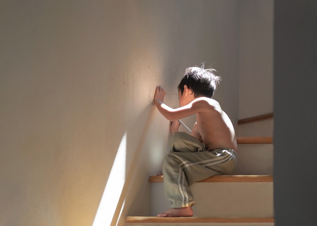 Niño asiático de 4 años en casa. Dibujar o pintar en la pared de la casa.