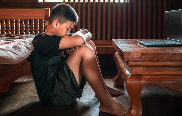 Niño asiático angustiado sentado en la oscuridad emoción triste y triste cara depresión niños concepto