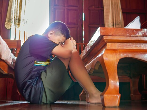 Niño asiático angustiado sentado en la oscuridad emoción triste y triste cara depresión niños concepto