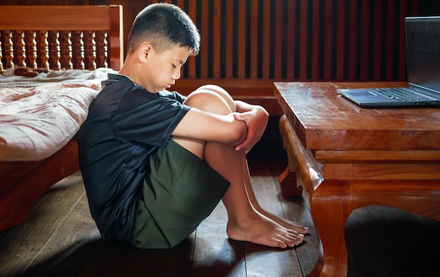 Niño asiático angustiado sentado en la oscuridad emoción triste y triste cara depresión niños