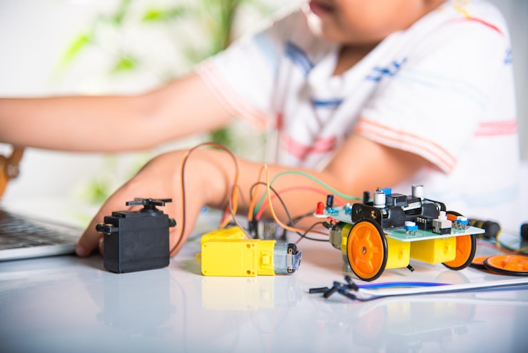 Foto niño asiático aprende codificación y programación con una computadora portátil para un automóvil robot arduino